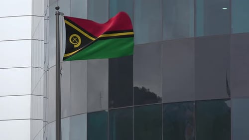 Waving Vanuatu Flag on Flagpole with Modern Building Background