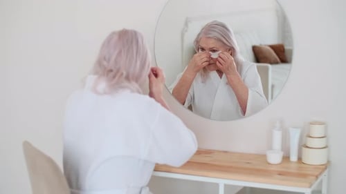 Senior Woman Applying Eye Patches in Mirror