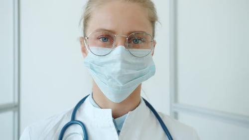 Slow Motion of Young Woman Doctor in Swite Suit and Medical Mask Standing in Clinic