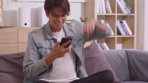 Happy Young Adult Celebrates Success on Smartphone