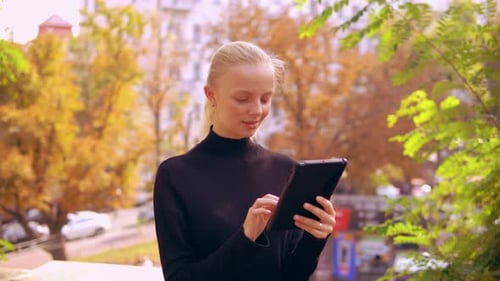 Woman Uses Tablet in Autumn Urban Park