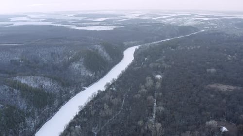 Beautiful flight in winter over snow-covered fields. Winter forest and river from above.