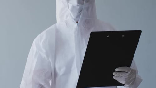 Medical Worker in Protective Gear Points Thermometer