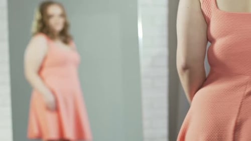 Mädchen mit zusätzlichem Gewicht bewundert Reflexion im Spiegel, bläst sich Kuss