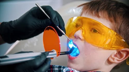 Dentist Curing Light on Child's Teeth