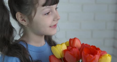 Little Girl Smelling Colorful Tulips at Home