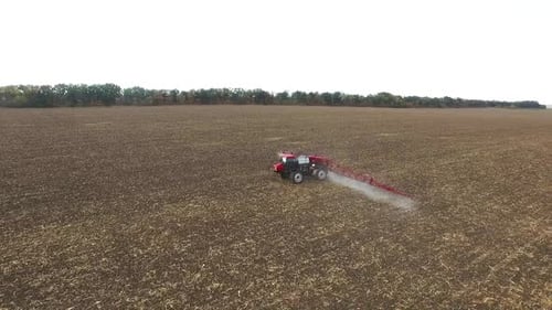 Roter Traktor pflügt den Feldmais, Luftaufnahme