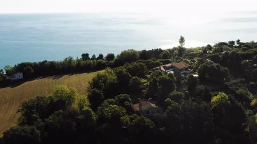 Drone Flying Down Over Beautiful Green Mediterranean Seaside Hills Towards Amazing House on Sunny