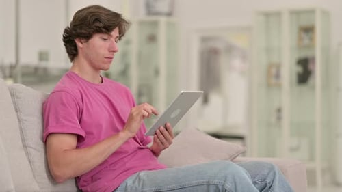 Young Adult Using Tablet on Couch at Home