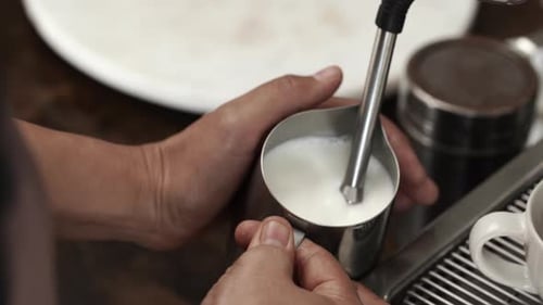Barista Steaming Milk for Coffee Drink in Cafe