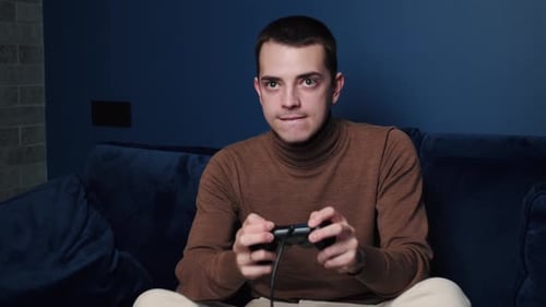 Man Focused on Video Game Controller at Home
