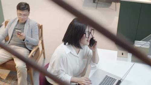 Businesswoman Talking on Phone, Using Laptop in Office