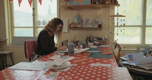 Female artist painting in her studio with water colors and pencils