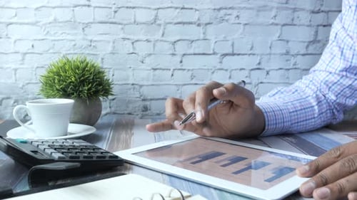 Man's Hand Working on Digital Tablet at Office Desk, Using Self Created Chart