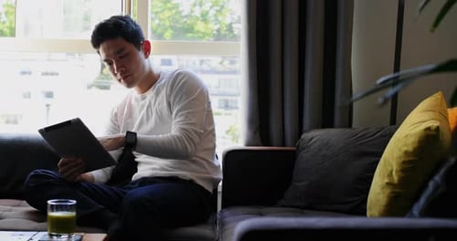 Man Relaxing at Home Using Tablet Device