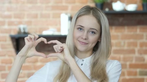 Young Woman Makes Heart Shape with Hands