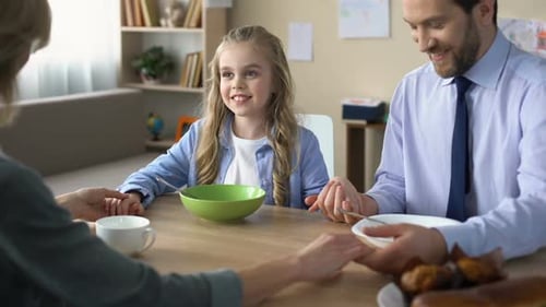 Loving Family Holding Hands at Breakfast Table