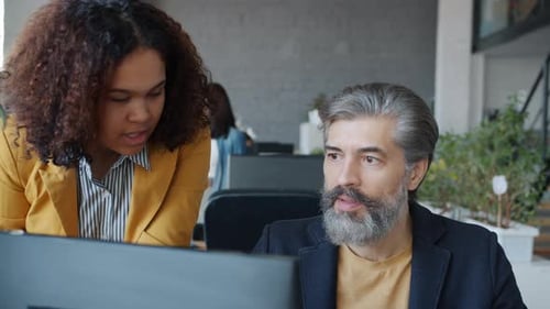 African American Woman and Caucasian Man Talking Using Computer in Shared Office