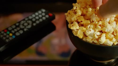 Close up, A man eating popcorn while watching a movie in the living room.