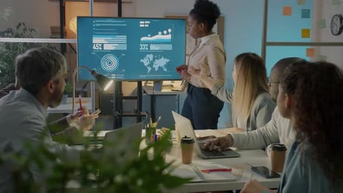 African American Woman Presenting Business Ideas to Diverse Group of Colleagues Pointing at Digital
