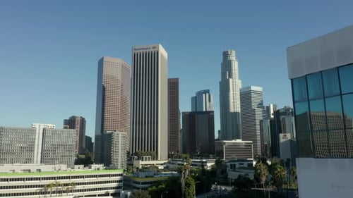 AERIAL: Reveal of Downtown Los Angeles, California Skyline Behind Building with Glass Windows at