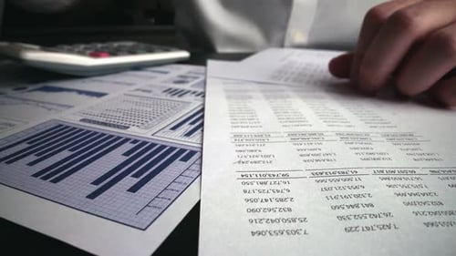 Accountant Analyzing Business Marketing Data on Paper Dashboard at Office Table