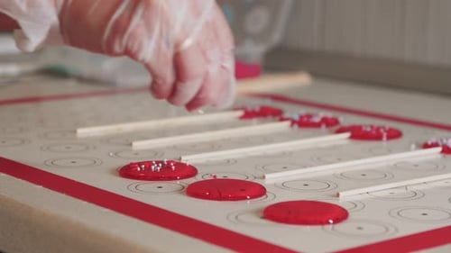Making Lollipops Pouring Sprinkling on Top of Red Caramel on the Paper