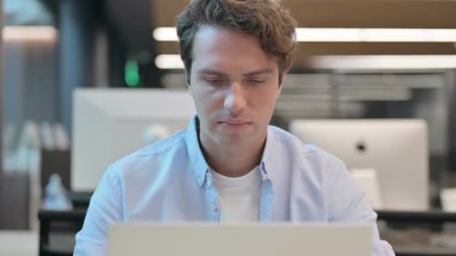 Nahaufnahme eines Mannes, der bei Verwendung des Laptops in die Kamera lächelt