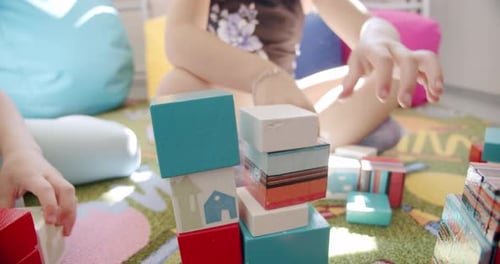 Close Up Kids Preschoolers Helping Building of Wooden Blocks Together Sit on Floor Carpet