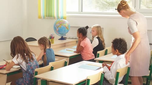 Teacher Assists Student in Elementary School Classroom
