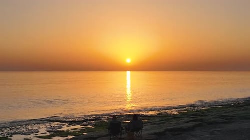 People sit on the beach and watch the sunset