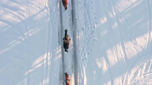 Aerial top tracking view of jockeys riding horses in winter snowy landscape