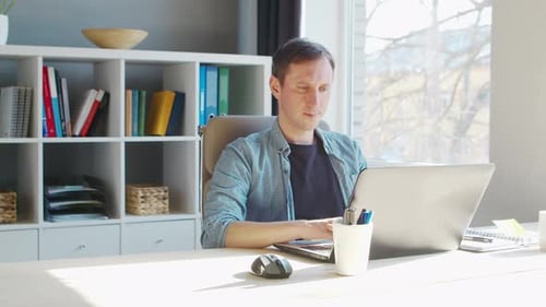 Young male entrepreneur works at home office at the computer.
