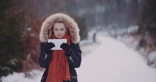 Woman Uses Tablet in Snowy Winter Forest