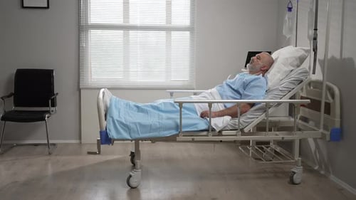 Senior Male Patient Lying in a Hospital Bed Wearing Oxygen Mask