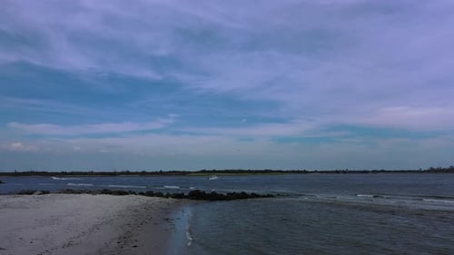 A low angle drone shot of an empty beach on a sunny day. The camera dolly out slowly over the sand a