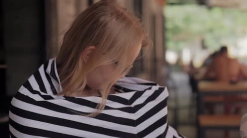 Woman Sits at Outdoor Cafe Table