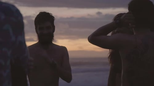 Freunde chatten in der Dämmerung am Strand