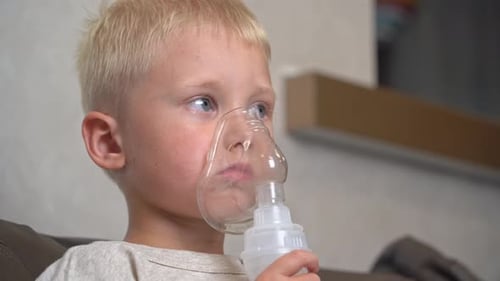 Boy doing inhalation while sitting on the couch