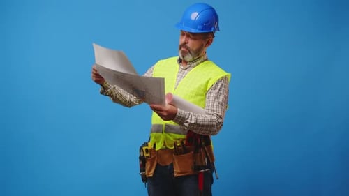 Construction Worker Reading Blueprints in Studio