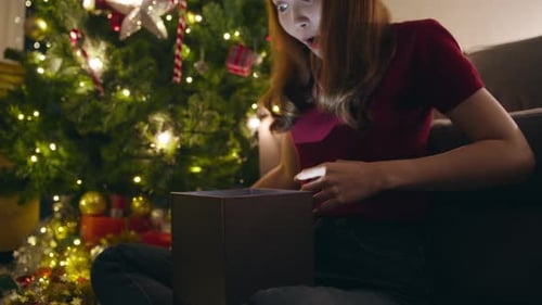 Woman Opening Magical Christmas Gift at Home