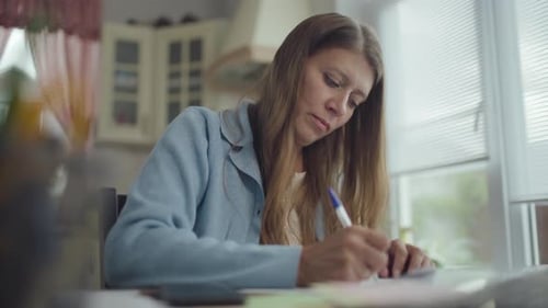 Woman Writing at Table in Bright Home Interior