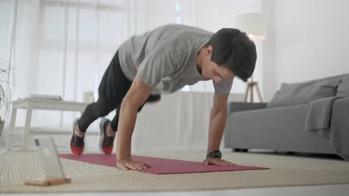 Handsome Young Man in a Gray T-Shirt and Black Shorts Does Sports at Home Online. Handsome Man