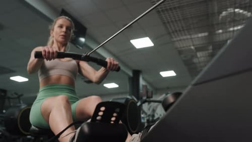 Woman Working Out on Rowing Machine at Gym