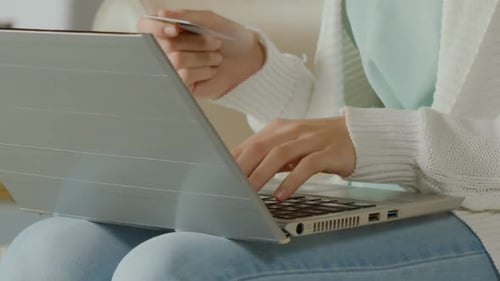 Mujer escribiendo el número de la tarjeta en la computadora portátil, comprar ropa en línea, primer plano