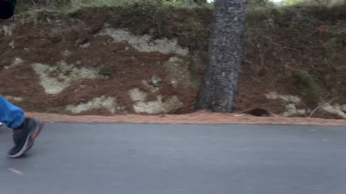 Pan of Legs eines Paares, das auf einem betonierten Weg durch den Wald wandert
