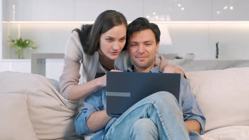 Couple Using Laptop on Couch in Bright Home