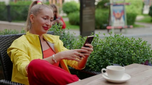 Rest in Coffee Shop with Street Terrace Woman is Using Smartphone for Chatting Online