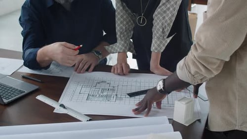 Multiethnic Architects Discussing Floor Plan in Office