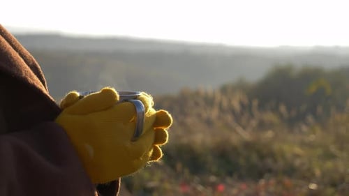 Person with Hot Drink Outdoors on Hillside